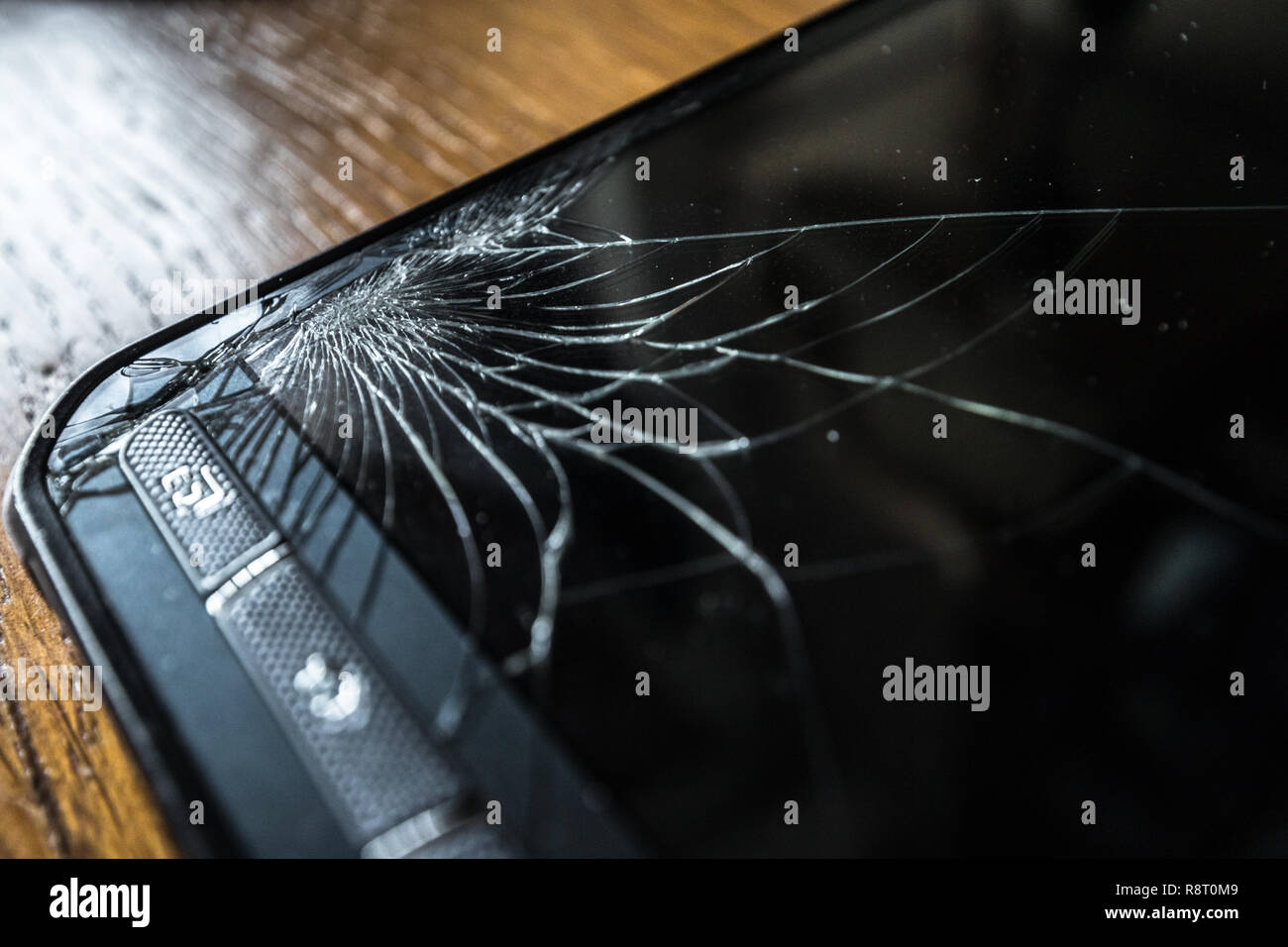 Incrinato toccare lo schermo dello smartphone su un tavolo di legno Foto Stock