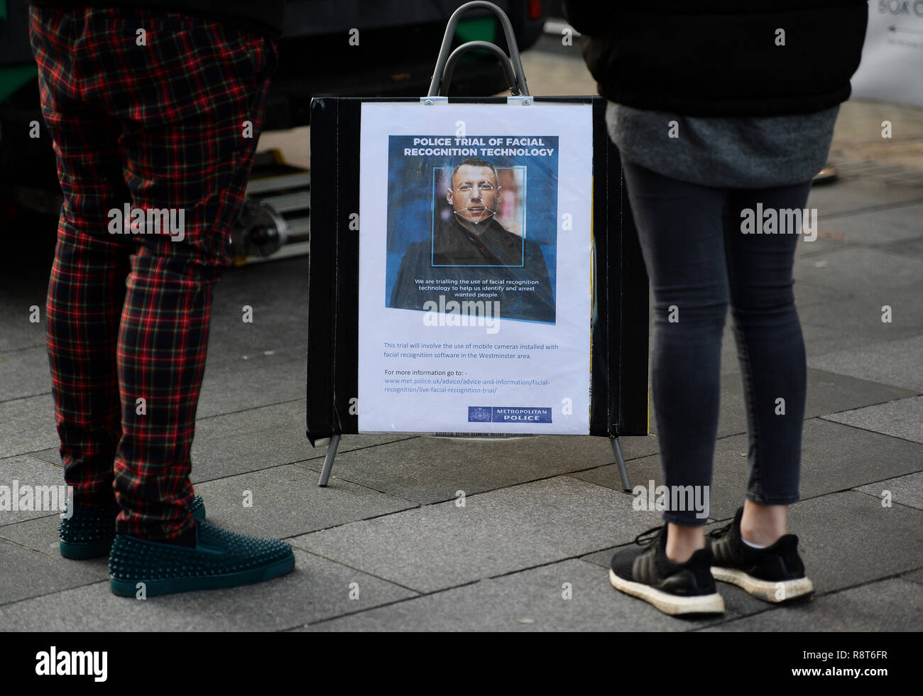 Le persone a smettere di guardare una scheda dettagli della tecnologia di riconoscimento facciale in uso nel quadrato di Leicester, Londra. Foto Stock