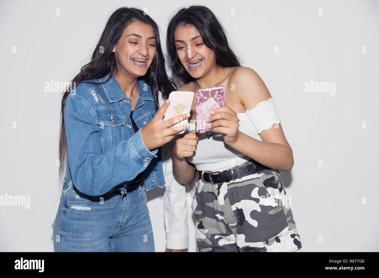 Teenage gemelle utilizzando i telefoni intelligenti Foto Stock