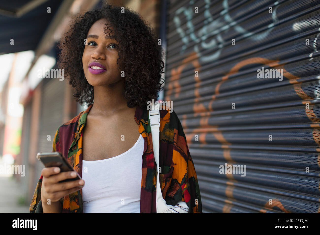 Giovane donna con smart phone sul marciapiede urbano Foto Stock