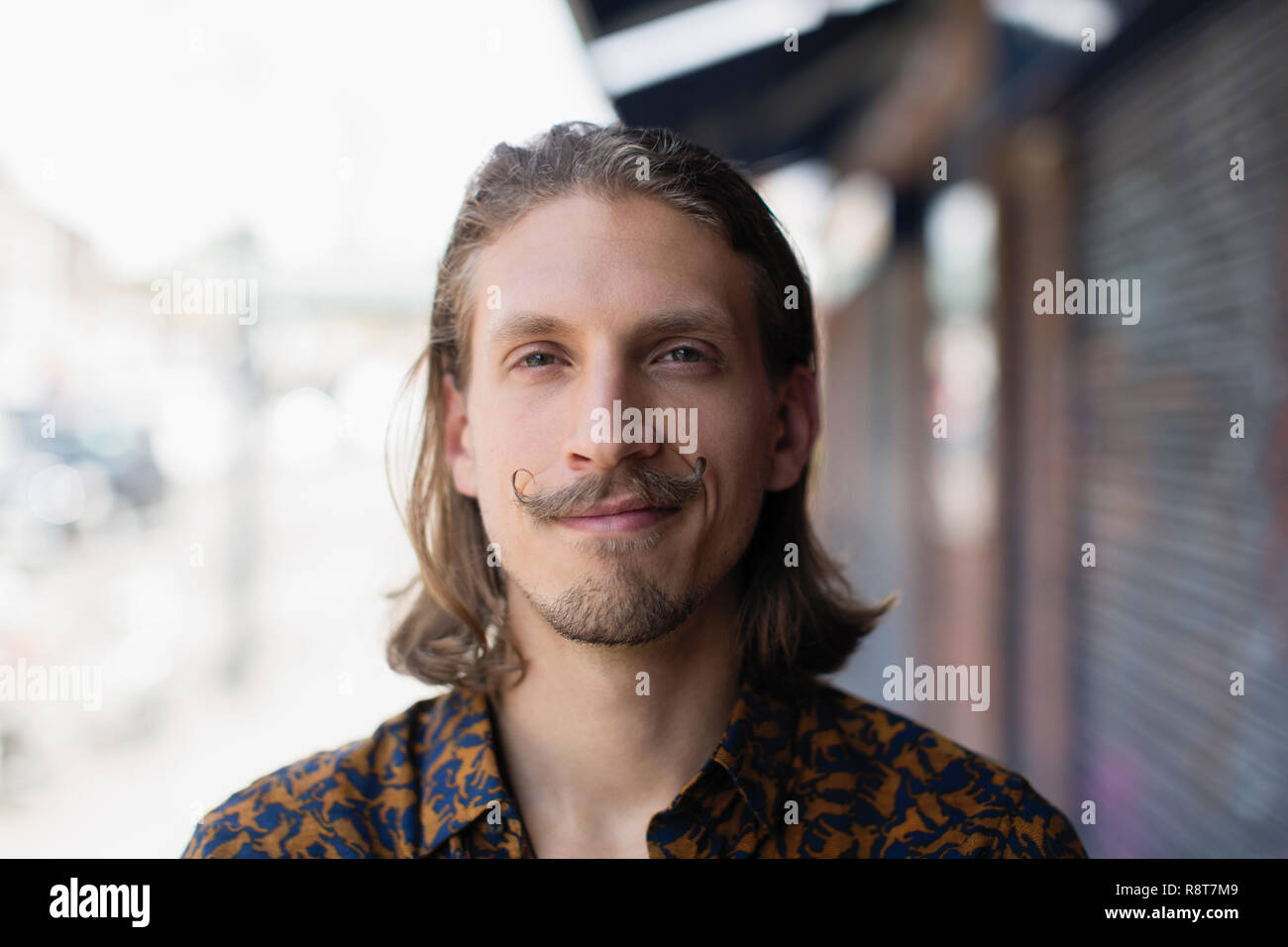 Ritratto fiducioso giovane maschio hipster con i baffi Foto Stock