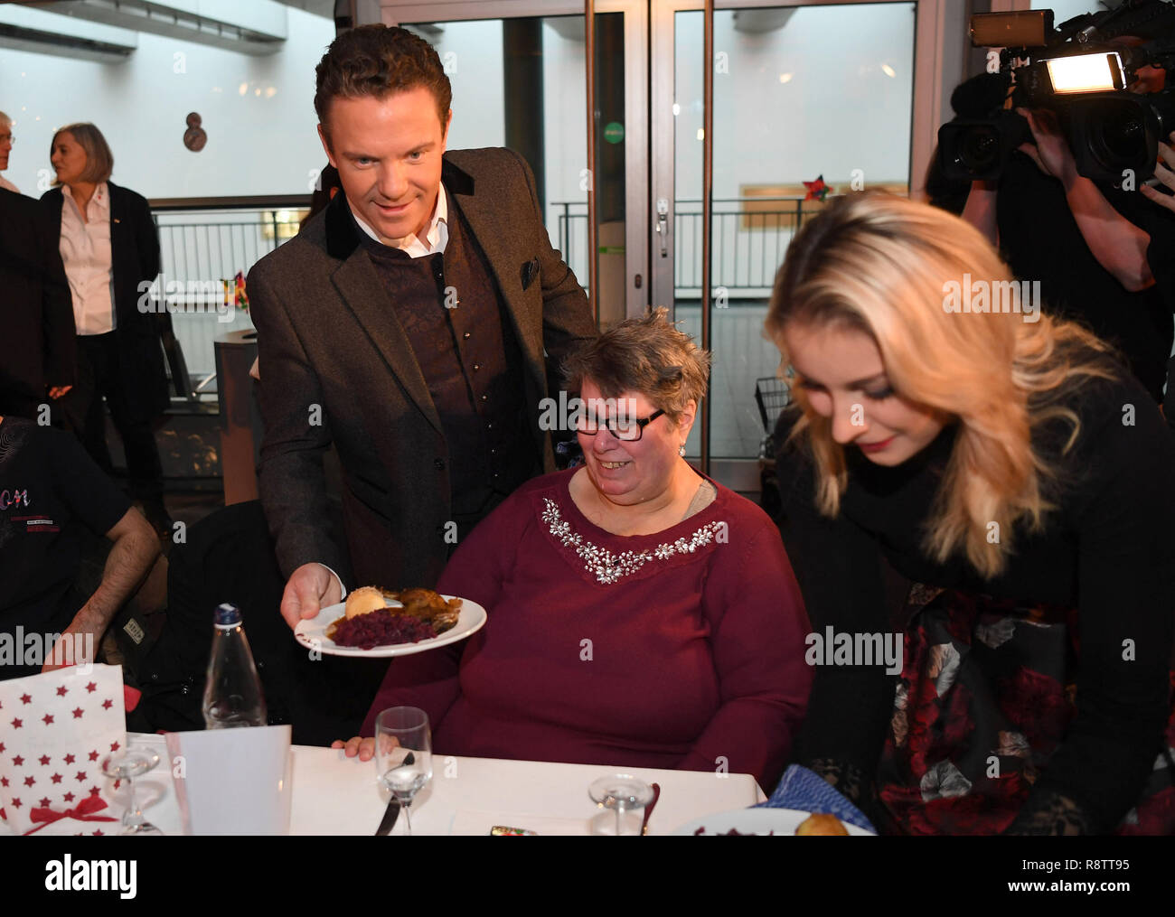 Bremen, Germania. Xviii Dicembre, 2018. Stefan Mross, trumpeter e il presentatore TV e la sua fidanzata Anna-Carina Woitschack (r), servirà apple cavolo rosso, gli gnocchi di patate e la gamba d'anatra insieme nella exhibition hall a beneficio cena "ein Festmahl - Ein Abend für bedürftige Menschen". Circa 800 uomini e donne, tra cui molte persone senza dimora sono stati invitati all'evento. Credito: Carmen Jaspersen/dpa/Alamy Live News Foto Stock