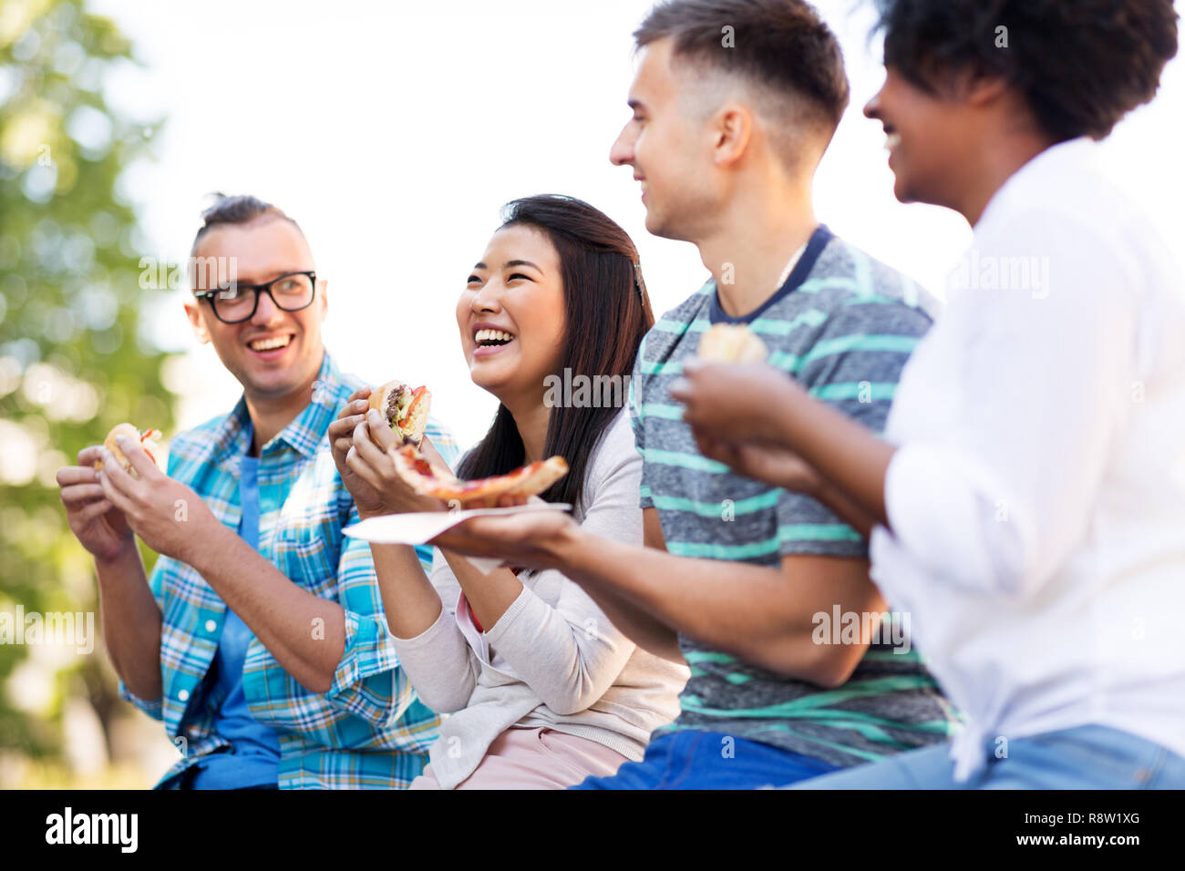 Happy amici mangiando panini e pizza all'aperto Foto Stock