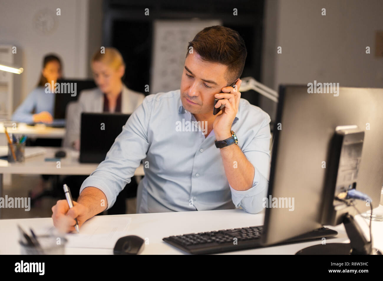 L'uomo chiamando sullo smartphone di notte office Foto Stock