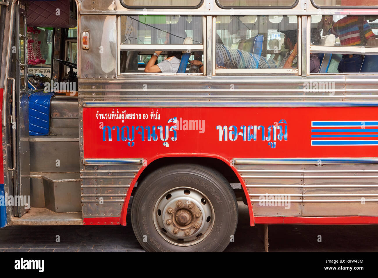 Dettaglio di Thai script sul lato di autobus extraurbani parcheggiato a Kanchanaburi central bus terminal, in Thailandia. Gli autobus sono tradizionalmente molto colori Foto Stock