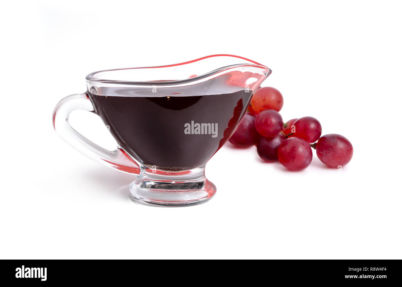 Aceto balsamico in ciotola con uva. Isolato su sfondo bianco. Foto Stock