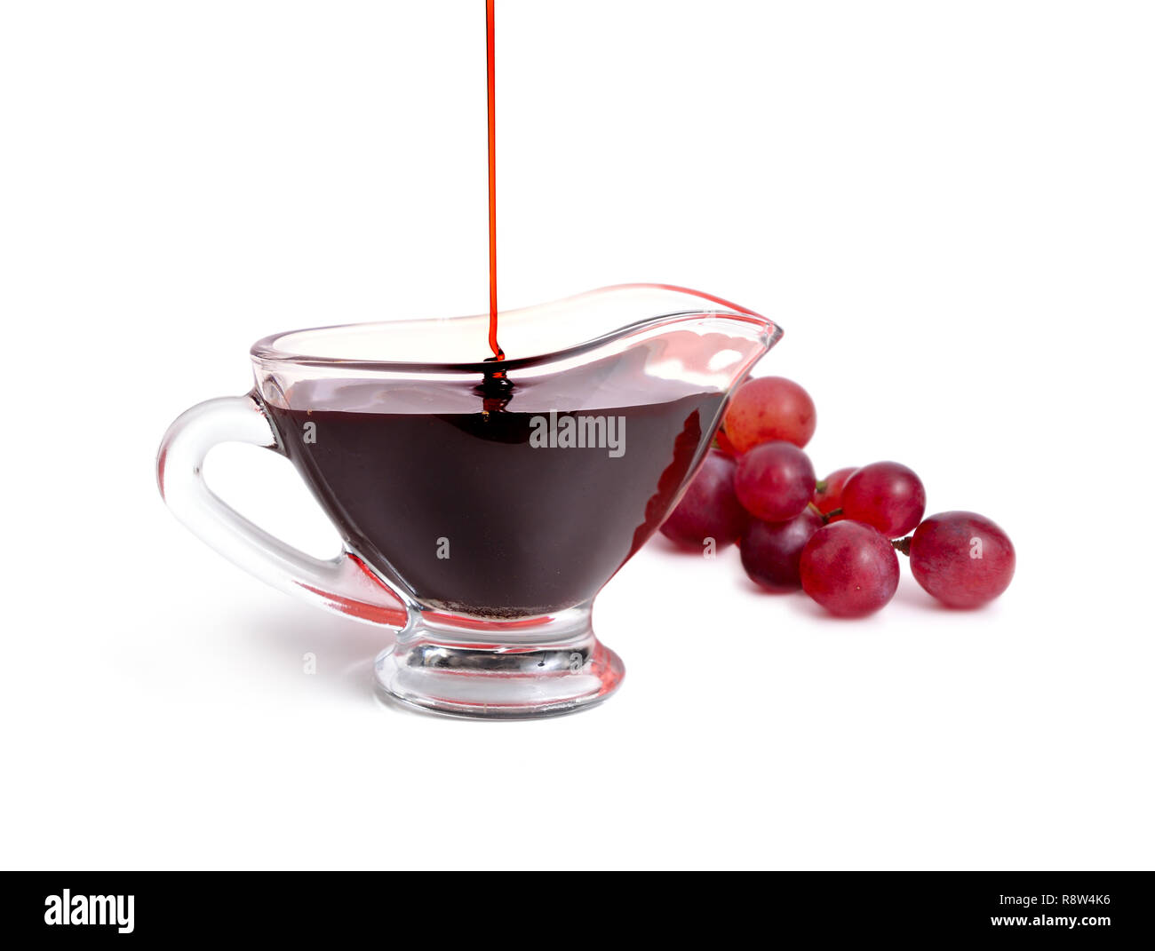 Aceto balsamico in ciotola con uva. Isolato su sfondo bianco. Foto Stock