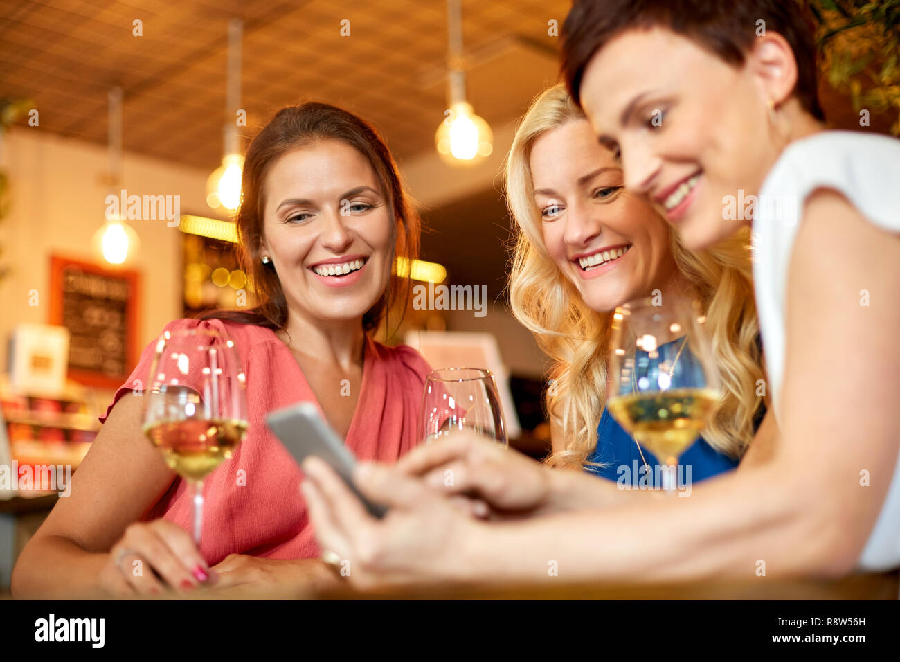 Le donne con lo smartphone a wine bar o ristorante Foto Stock