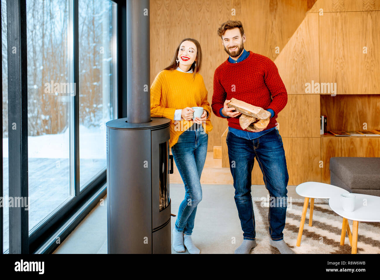 Ritratto di una giovane coppia in bright maglioni in piedi vicino al caminetto nella casa moderna Foto Stock
