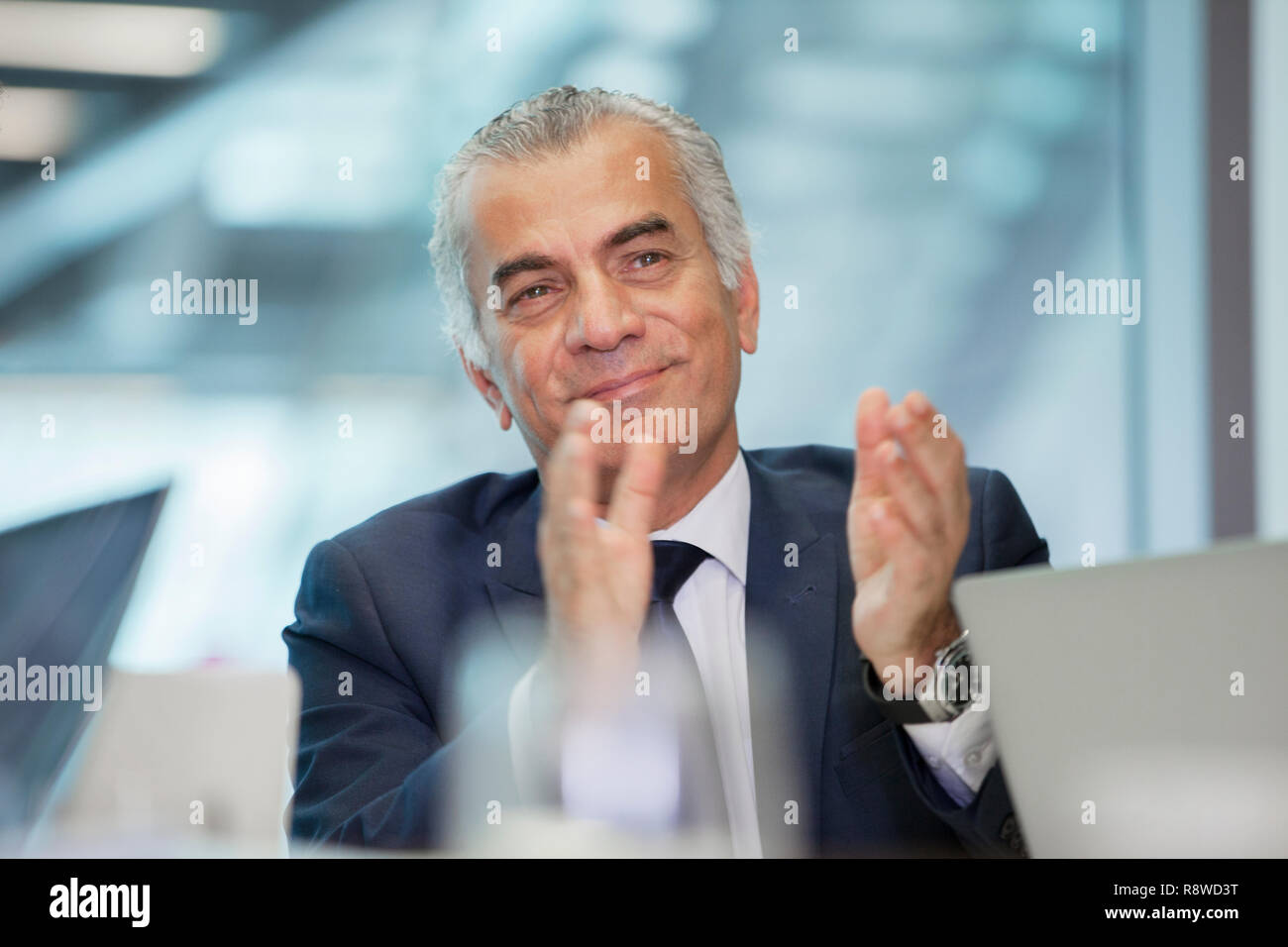 Sorridente e fiducioso imprenditore senior battendo le mani in riunione Foto Stock