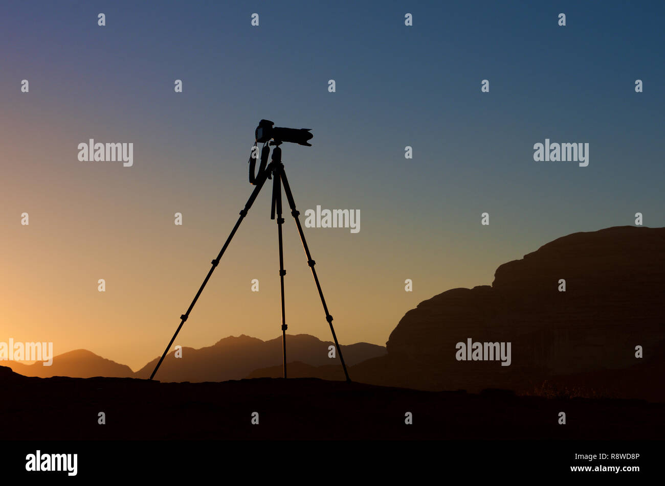 La fotocamera su un treppiede isolato in sunrise sfondo. silhouette della fotocamera su treppiede con le montagne sullo sfondo di sunrise, fotocamera pronta per scattare foto Foto Stock