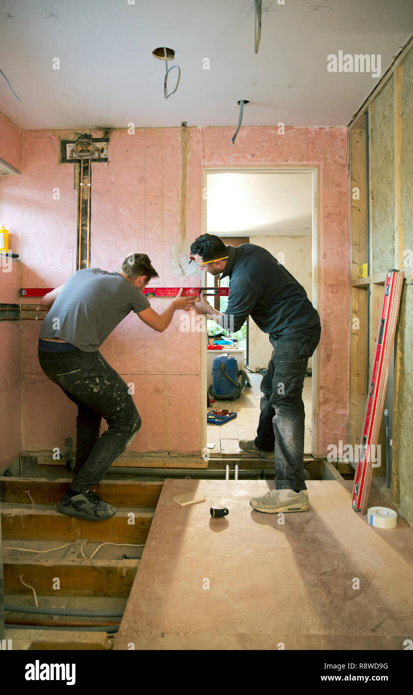 Lavoratori edili utilizzando lo strumento livello in casa Foto Stock