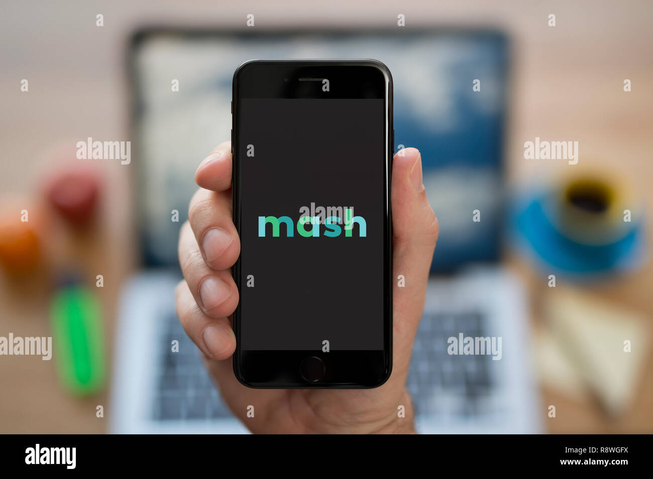 Un uomo guarda al suo iPhone che visualizza il logo Mash (solo uso editoriale). Foto Stock