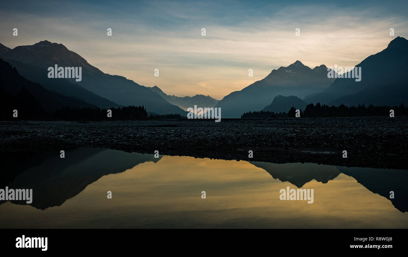 Banca di ghiaia nella Valle del Lech, Austria, con la riflessione del panorama di montagna Foto Stock
