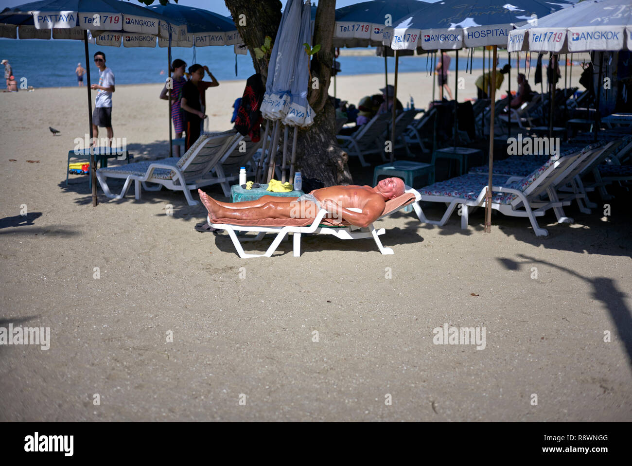 L uomo a prendere il sole su un lettino o poltrona reclinabile presso la spiaggia di Pattaya, Thailandia, Sud-est asiatico Foto Stock