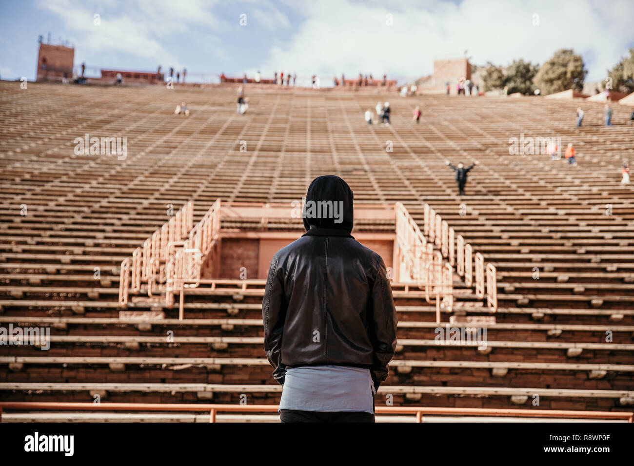 Ritratto simmetrica di persona in piedi su un palco di sognare mentre di fronte si erge Stadium posti a sedere presso l'anfiteatro all'aperto Concert Music Hall al di fuori Foto Stock