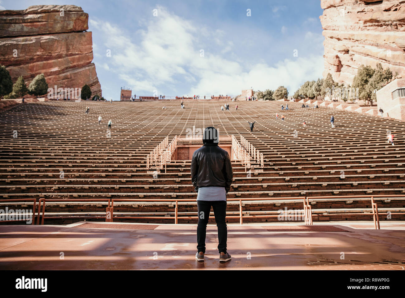 Ritratto simmetrica di persona in piedi su un palco di sognare mentre di fronte si erge Stadium posti a sedere presso l'anfiteatro all'aperto Concert Music Hall al di fuori Foto Stock