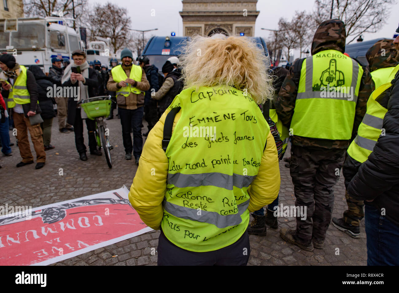 Giubbotti di giallo di dimostrazione (Gilets Jaunes) manifestanti contro il governo e il presidente francese a Champs-Élysées con slogan sul retro. Parigi, Francia. Foto Stock