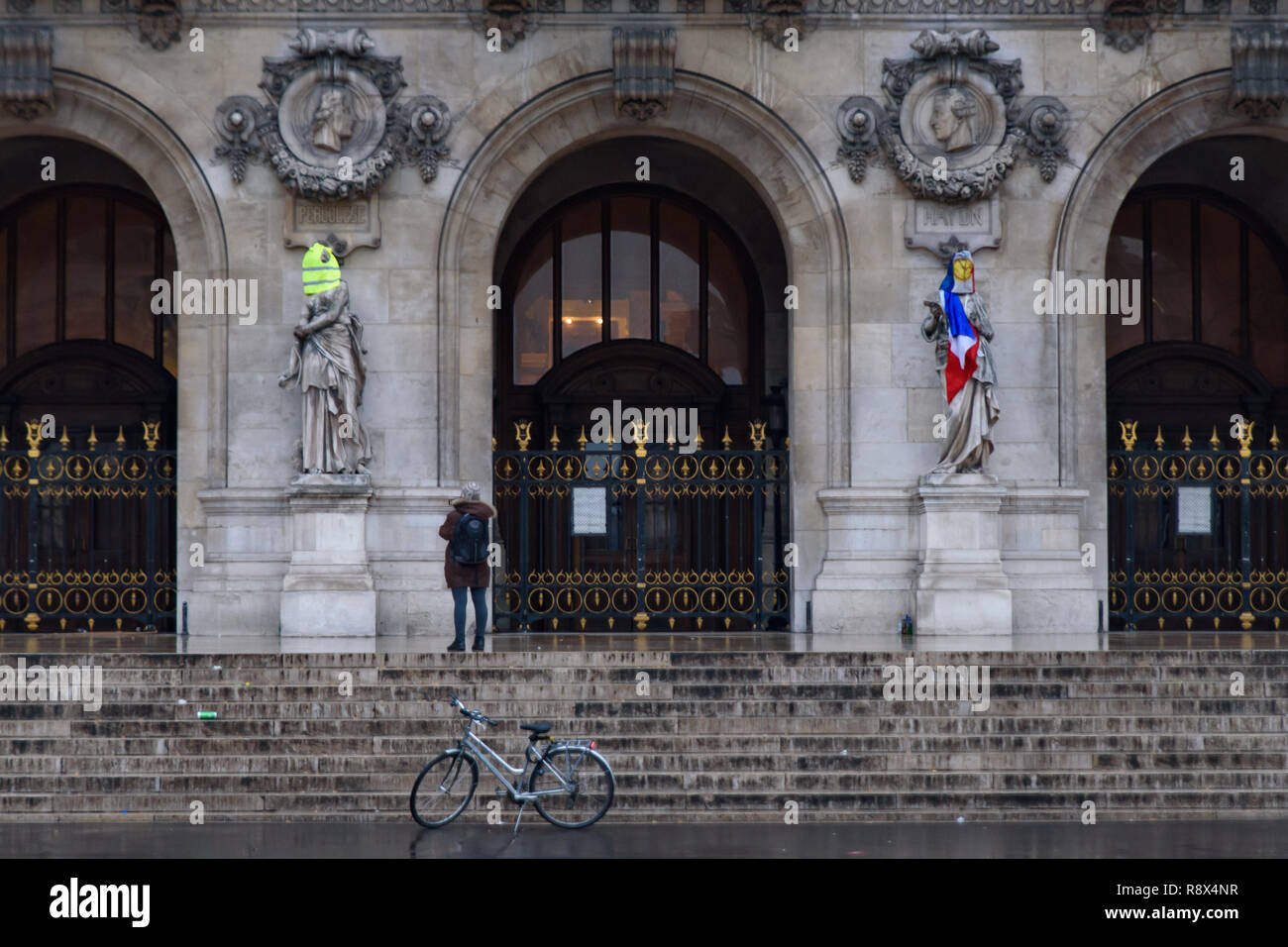 I manifestanti di giubbotti di giallo di dimostrazione (Gilets Jaunes) contro le tasse sul carburante, il governo e il presidente francese Macron mettere giubbotto di colore giallo e bandiera su Parigi o Foto Stock