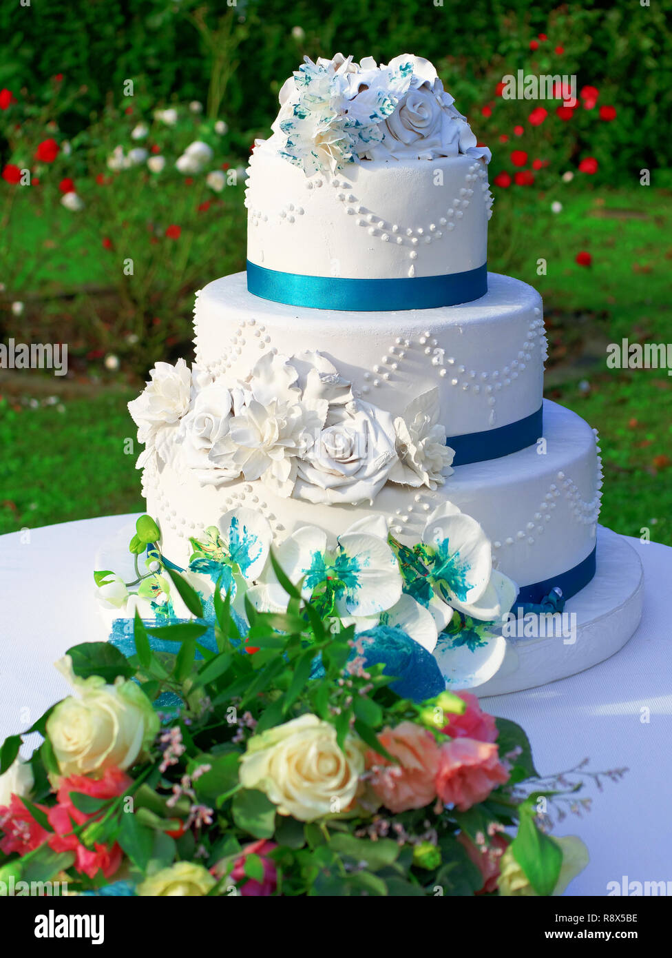 Torta nuziale decorata con fiori all'aperto Foto Stock