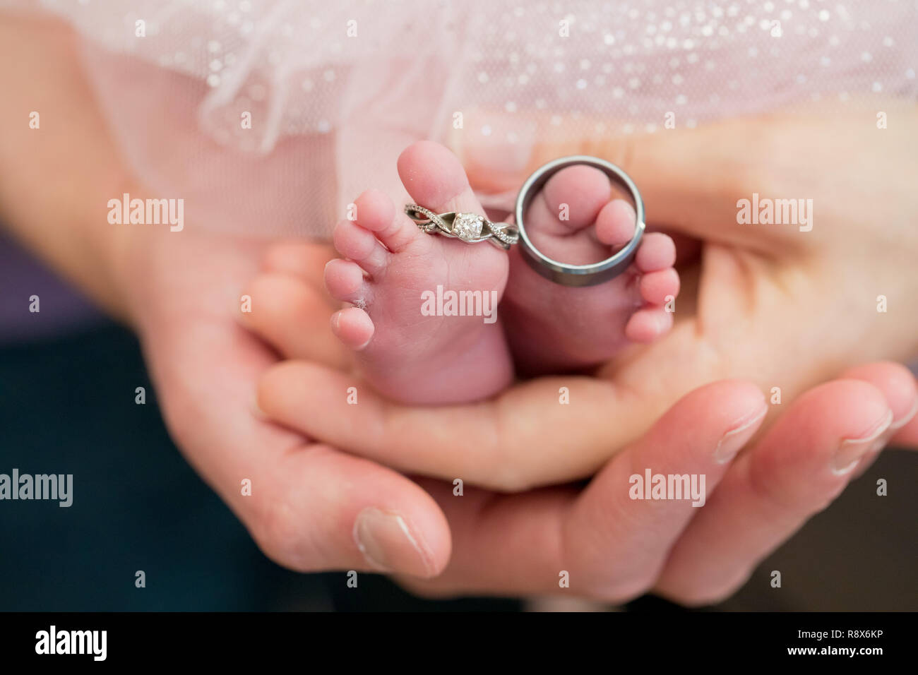 Gli anelli di nozze sul neonato piedi con i genitori Mani Foto Stock