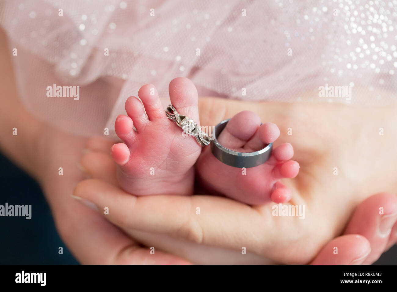 Gli anelli di nozze sul neonato piedi con i genitori Mani Foto Stock