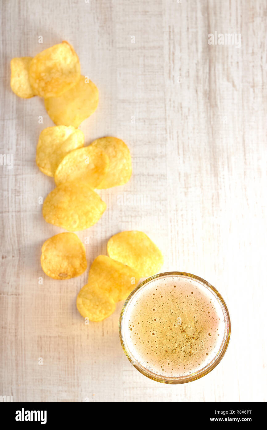Un bicchiere di freddo, birra chiara con trucioli sparsi sul tavolo. copia spazio. La vista dalla cima del minimalismo. Foto Stock
