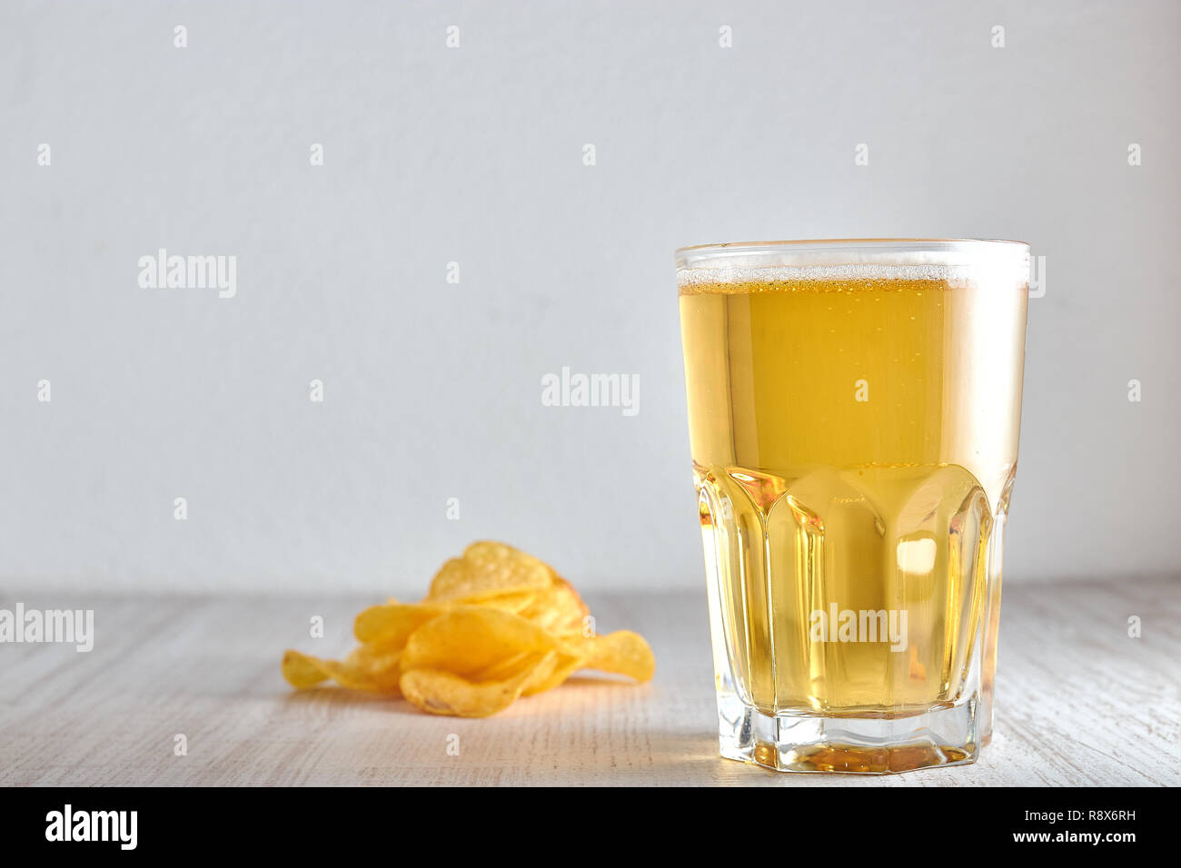 Un vetro a freddo, frumento, birra chiara con trucioli sparsi sul tavolo. copia di spazio. Foto Stock
