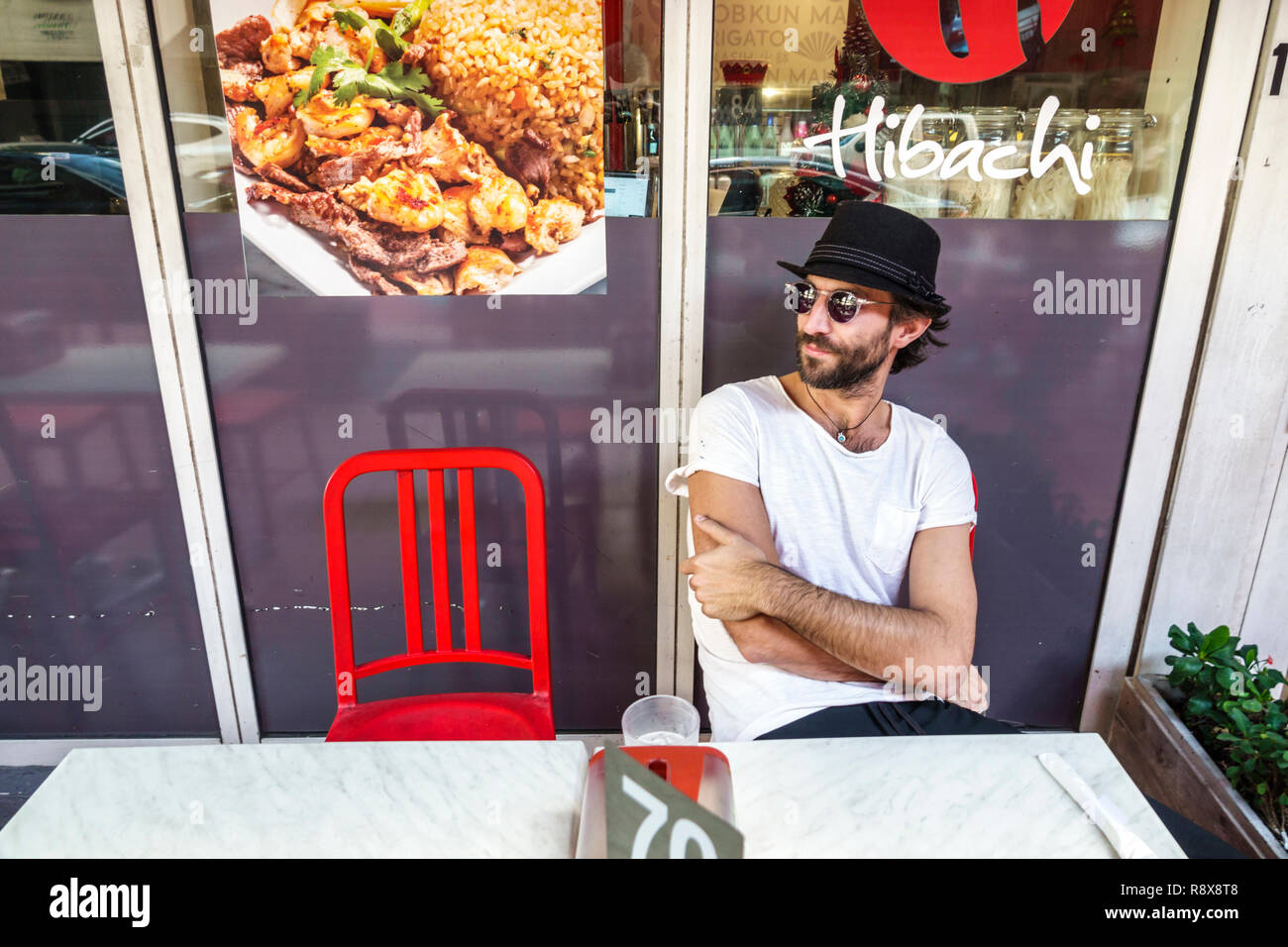 Miami Florida,Flagler Street,Downtown,single,adulti uomo uomo uomini maschio,tavolo seduto,guardare,cappello fedora,occhiali da sole,visitatori viaggio t Foto Stock