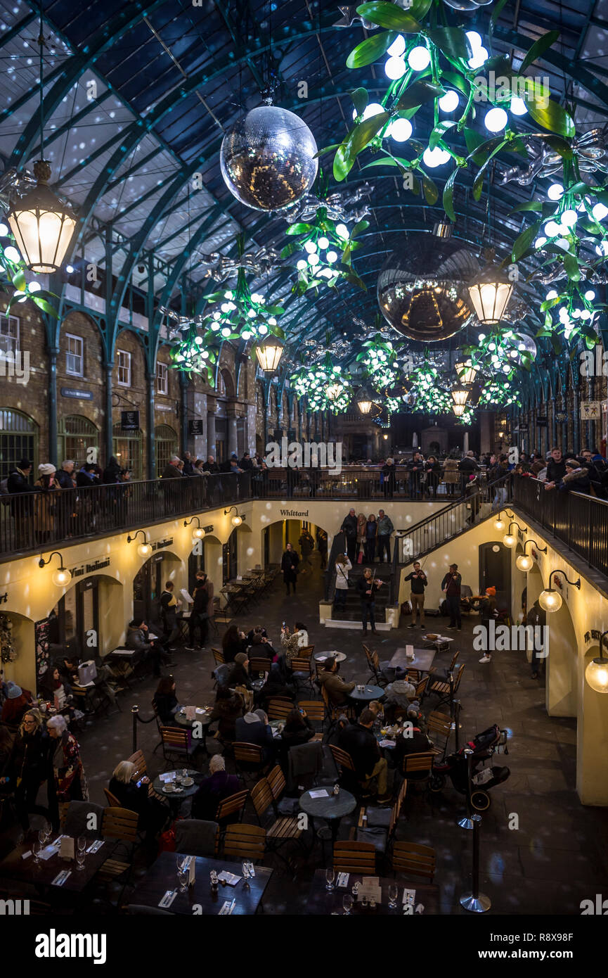 Londra - 26 novembre 2018: i turisti passeggiare sotto grandi decorazioni di Natale Illuminazione dell'architettura neoclassica di Covent Garden. Foto Stock