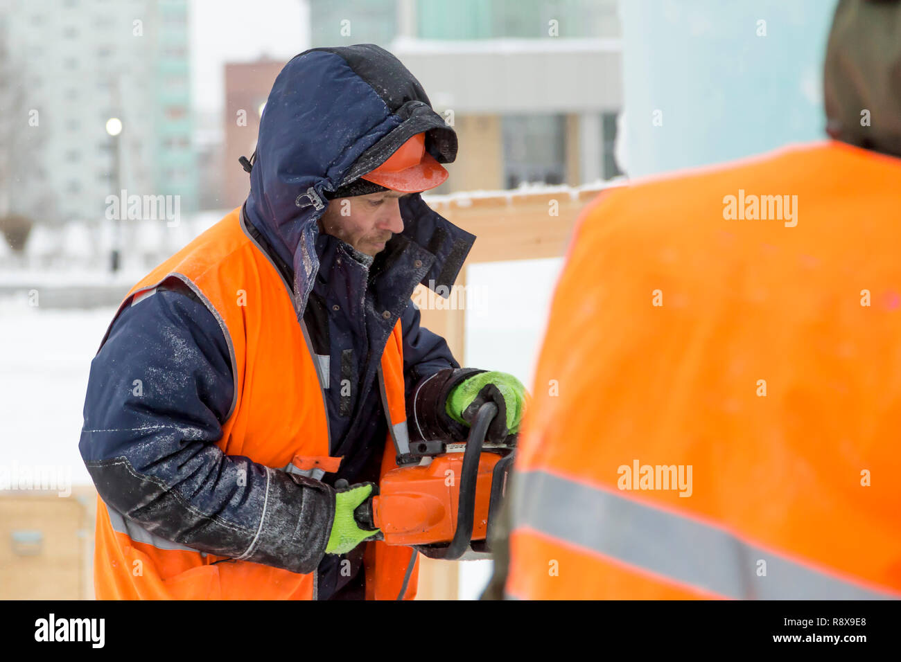 Il programma di installazione di lavoro in un casco protettivo e giubbotto con una motosega nel profilo Foto Stock