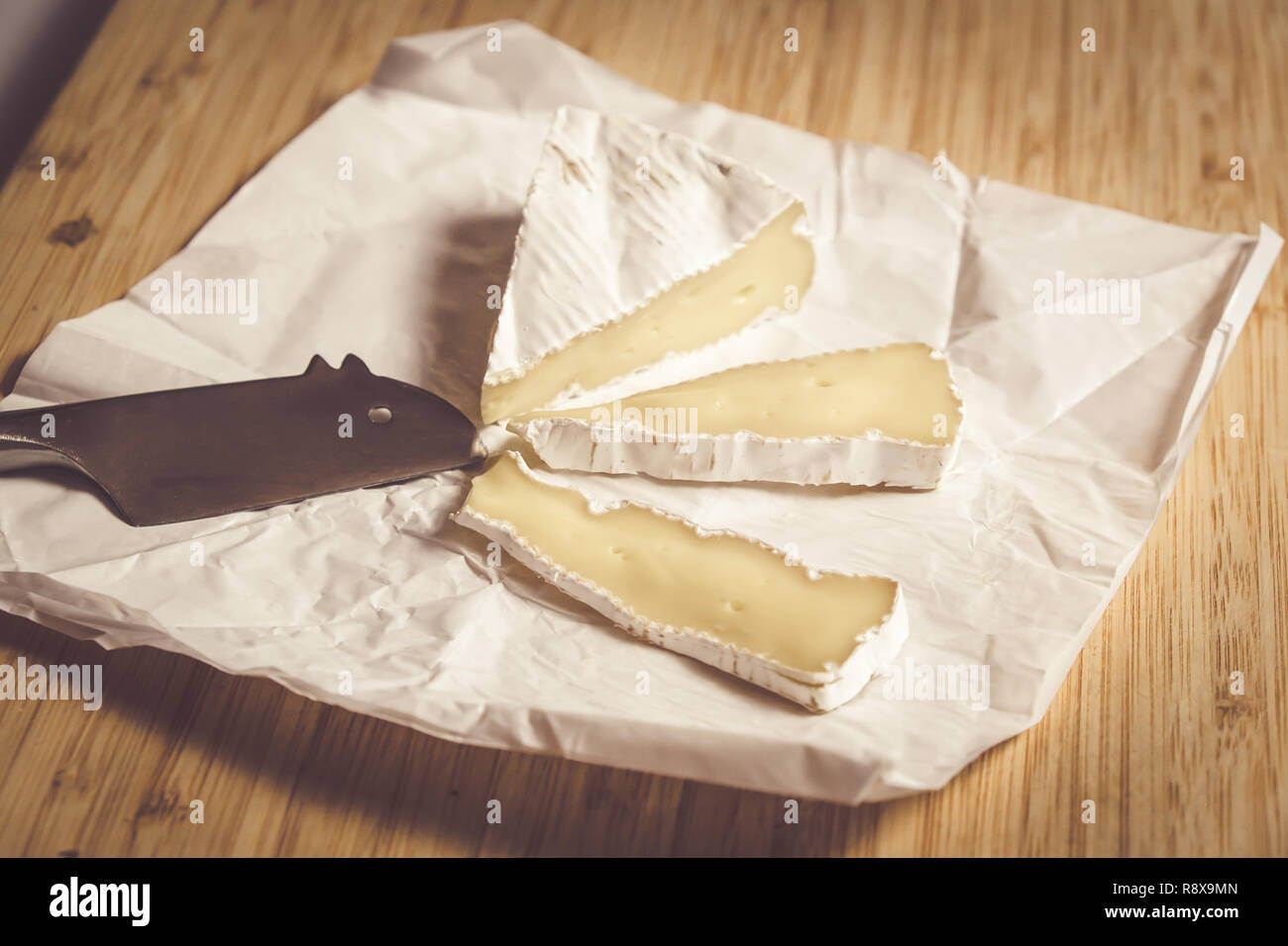 Mature di età Formaggio Brie tagliato a fettine su un foglio di carta con il mouse coltello sagomato Foto Stock