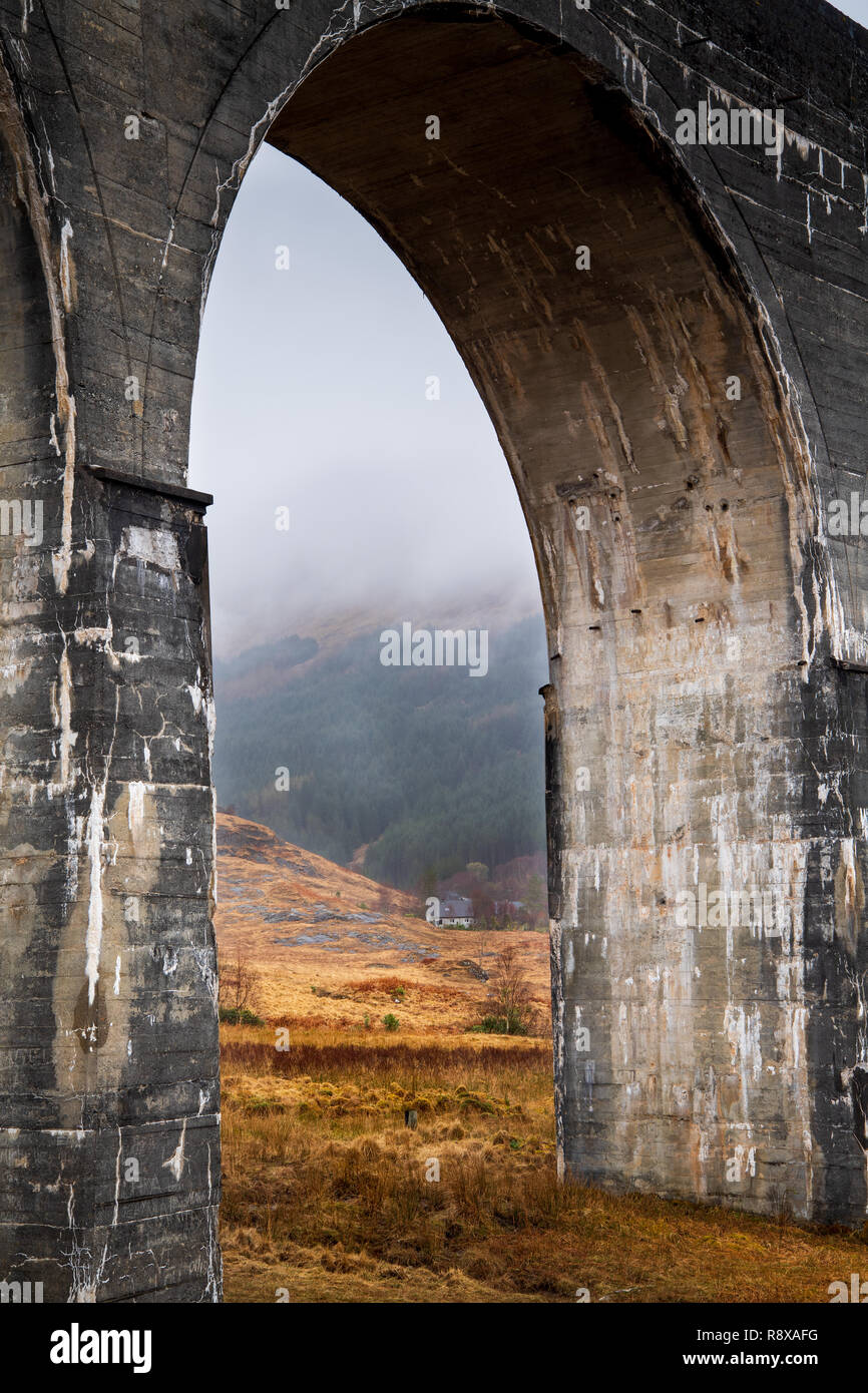 White cottage in pietra immerso nelle highlands scozzesi incorniciata da un viadotto archway. Foto Stock