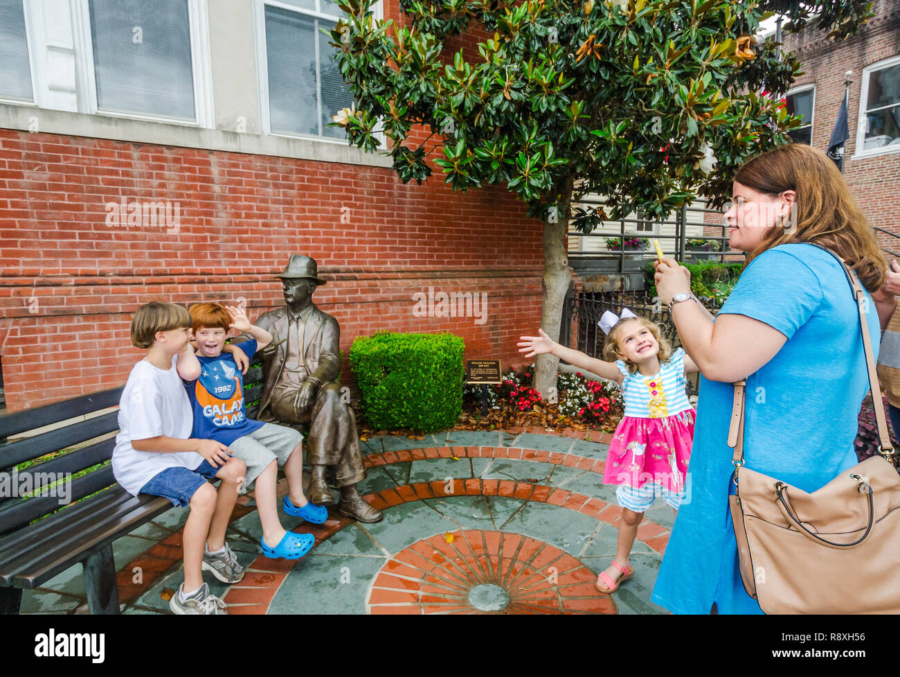 Una donna fotografie i suoi figli con una statua di bronzo di William Faulkner, 31 maggio 2015, a Oxford, Mississippi. Foto Stock