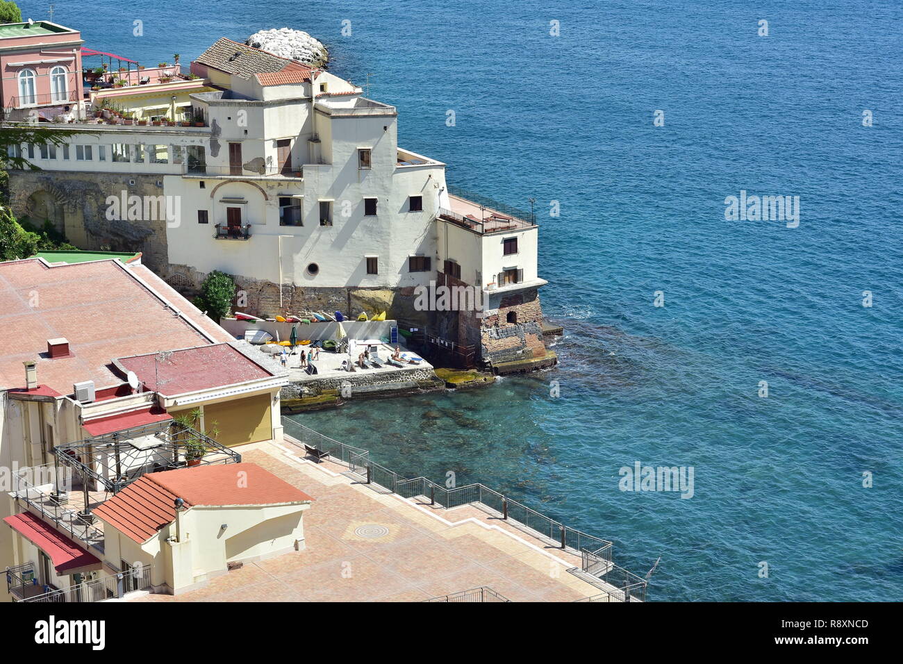 Terrazza mediterranea case costruire sulle ripide pareti rocciose lungo la costa scoscesa a destra sopra il mare blu superficie. Foto Stock