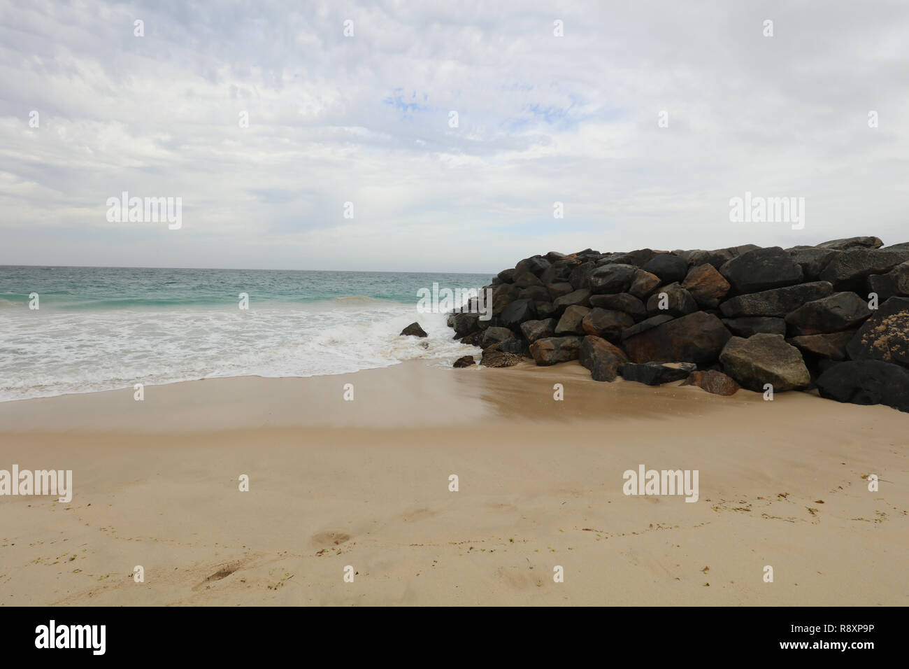 Grandi e pesanti rocce formando un groyne perpendicolare alla riva della spiaggia della città, vicino a Perth, Western Australia, limitando il movimento e la perdita di sabbia. Foto Stock