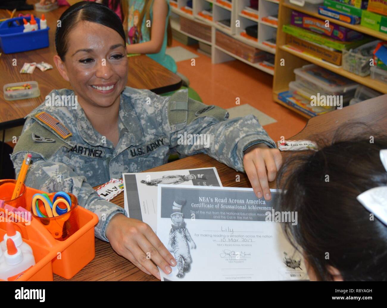 Stati Uniti Esercito personale di riserva Sgt. Claudia Martinez con il quarto supporto comando (Expeditionary) mani leggere attraverso l'America certificati per gli studenti al Kinder Ranch elementare nella San Antonio, TX, Marzo 10, 2017. Foto Stock