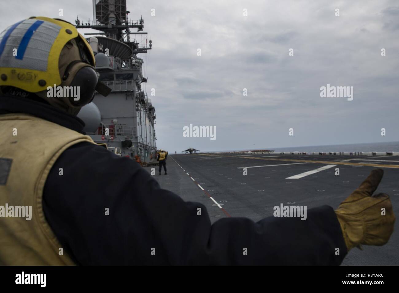 Un marinaio di segnali al pilota di un AV-8B Harrier durante operazioni di volo nell'Oceano Pacifico a bordo della USS Bonhomme Richard (LHD 6), 9 marzo 2017. Marines e marinai del trentunesimo MEU imbarcata a bordo della USS Bonhomme Richard (LHD 6), parte dell'Bonhomme Richard anfibio gruppo Readiness, come parte del loro annuale primavera pattuglia dei Indo-Asia-regione del Pacifico. Il trentunesimo MEU, imbarcato sulle navi anfibie del Expeditionary Strike gruppo 7, ha la capacità di rispondere a situazioni di crisi o di contingenza con un preavviso di pochi istanti. Foto Stock