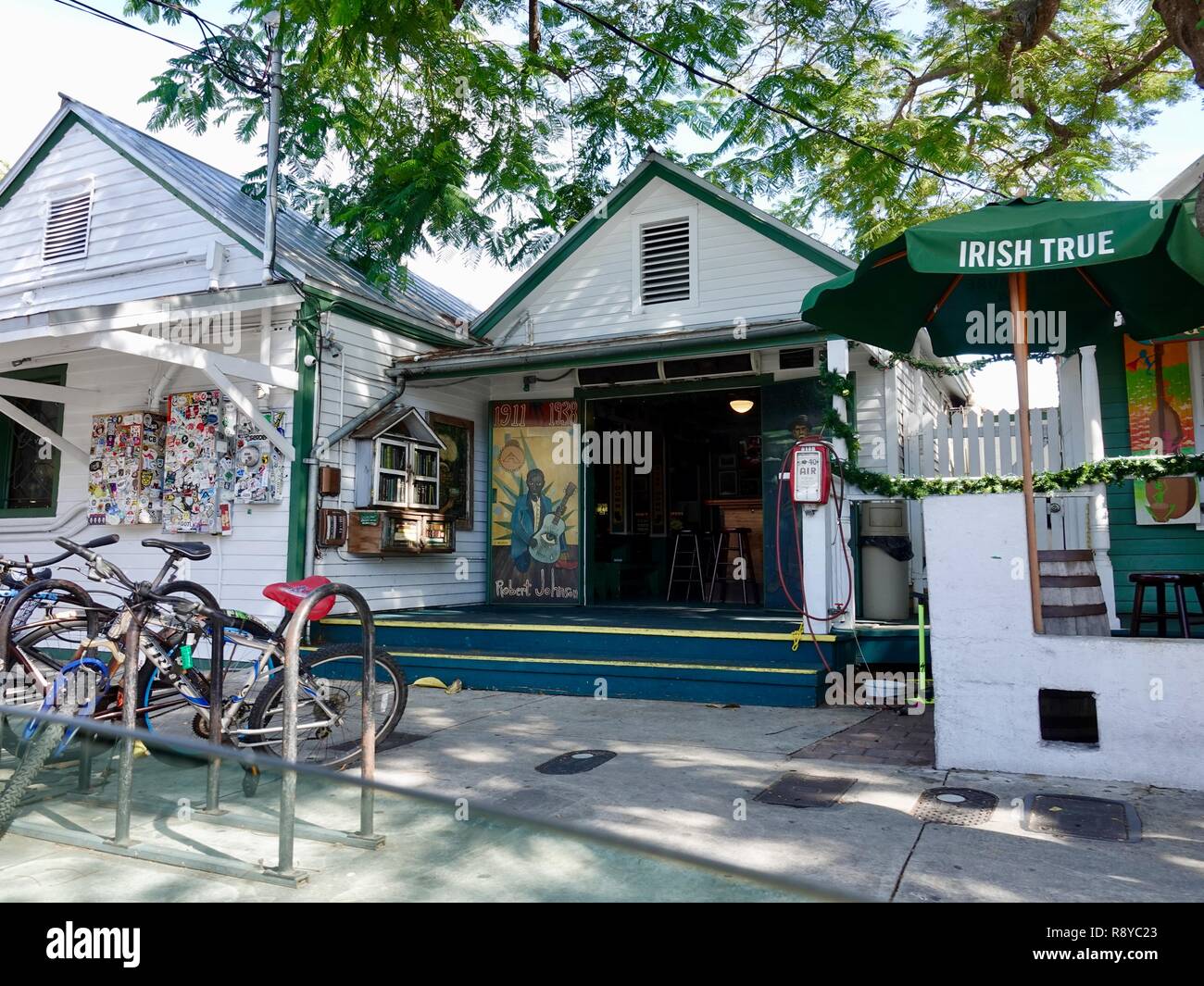 Ombroso vista sul marciapiede di classici del Key West Florida, edifici a pappagallo verde bar sulla strada di Whitehead, murale con Omaggio a Robert Johnson. Foto Stock