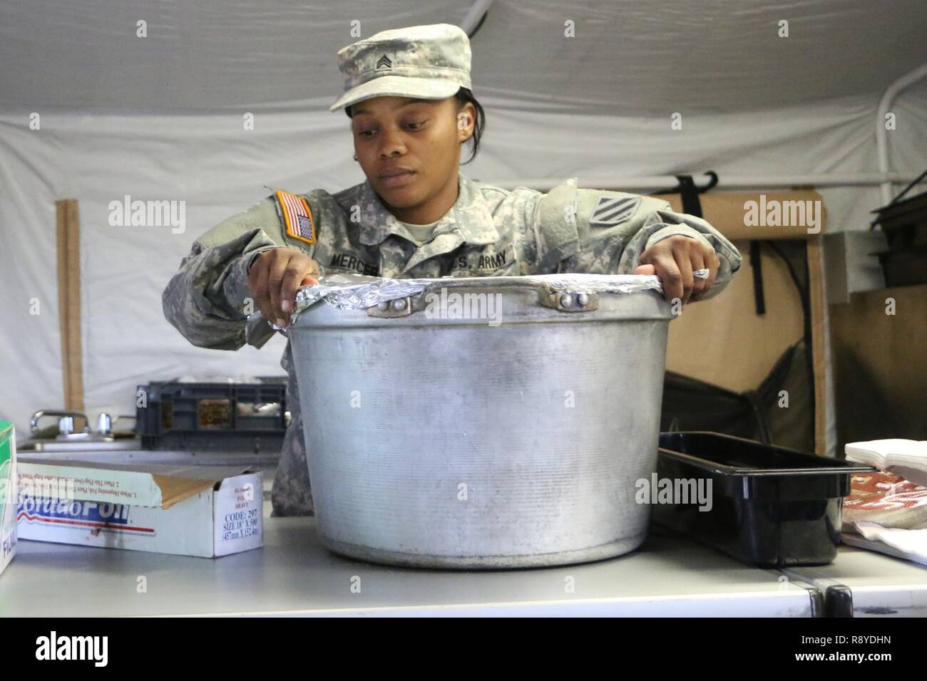 Sgt. Tichina Mercer, culinario sottufficiale 703rd con supporto vigili del Battaglione, 2° della brigata di fanteria combattere la squadra, terza divisione di fanteria, copre una pentola di verdure Febbraio 23, 2017 a Fort Stewart, Ga. Soldati preparati pasti caldi in un campo cucina durante un battaglione convoglio live-fire esercizio. Foto Stock