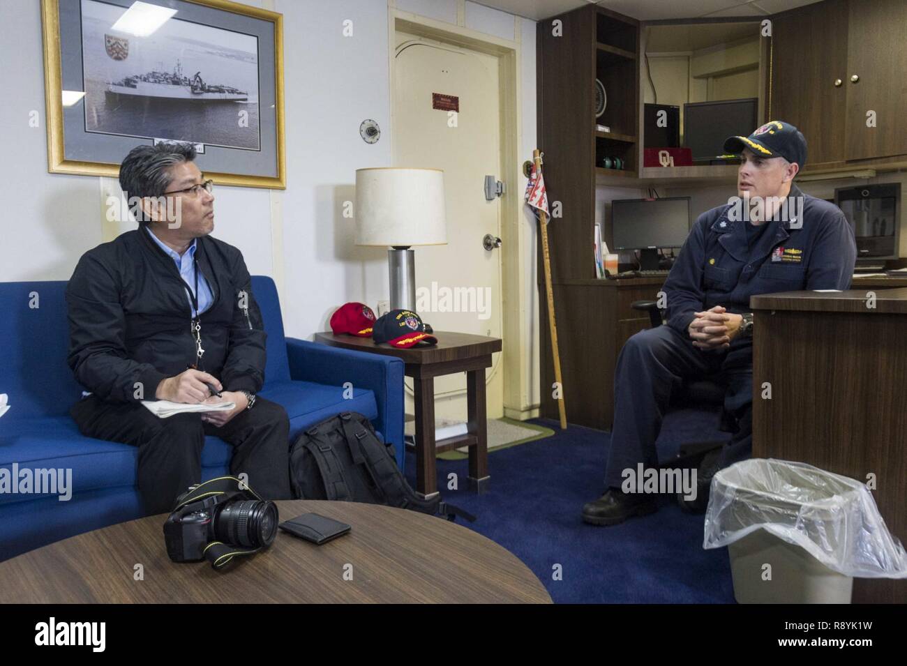 OKINAWA, in Giappone (17 marzo 2017) Comandante della Cmdr. Steven Wasson parla con Sunao Gushiken, un reporter per Giapponese quotidiano nazionale La Asahi Shinibum, durante un media tour a bordo del dock anfibio sbarco nave USS Ashland (LSD 48). Ashland, parte dell'Bonhomme Richard Expeditionary Strike gruppo, con avviato 31 Marine Expeditionary Unit, è su una pattuglia di routine, operando in Indo-Asia-regione del Pacifico per rafforzare le partnership e di essere una pronta risposta in vigore per qualsiasi tipo di emergenza. Foto Stock