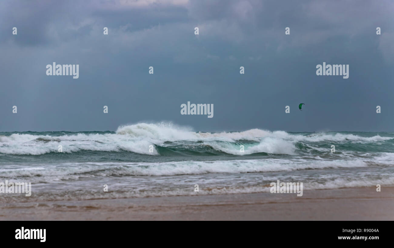 Surfer's paracadute in un cielo tempestoso sopra le onde spumeggianti del Mare Mediterraneo. Israele Foto Stock