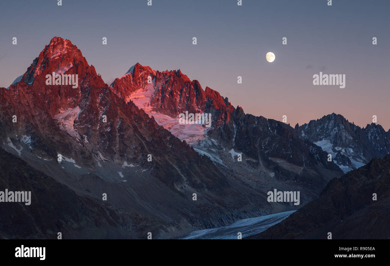 L'ultimo, la calda luce del sole sul picco di montagna Aiguille D'Argentiere durante un autunno sorgere della luna. Chamonix, Francia. Foto Stock