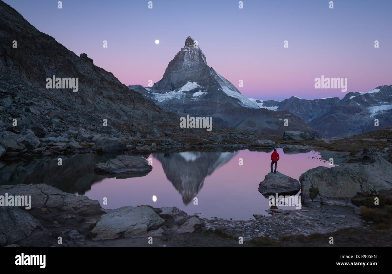 Escursionista su una roccia nel Riffelsee all'alba, godendo della vista sul Cervino. Foto Stock