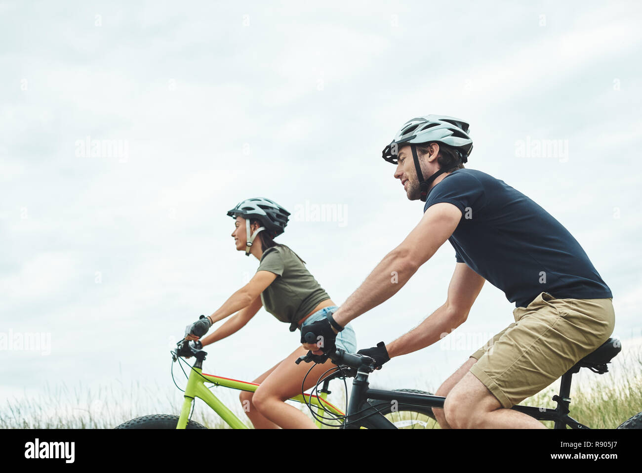 Coppia giovane sono escursioni in bicicletta su fatbikes e nei caschi. Foto ritagliata Foto Stock
