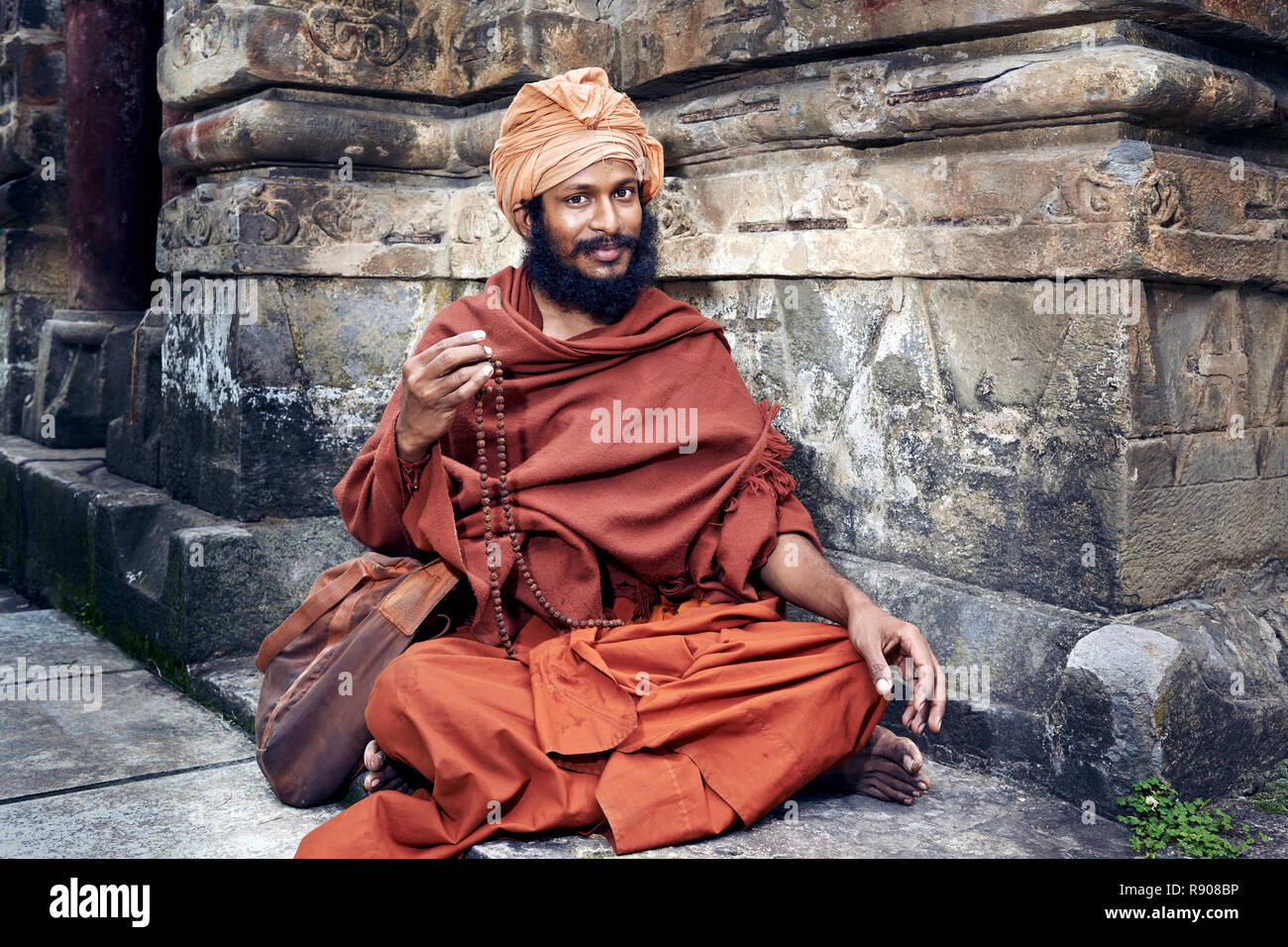 Naggar, India - 17 Luglio: Giovani yogi si siede vicino al tempio di Krishna. Si ripete il mantra segreto utilizzando un rosario. Il salmodiare 108 nome sacro di Dio. Luglio 1 Foto Stock