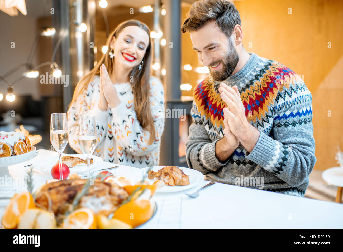 Coppia giovane avente una cena di gala seduti insieme nella casa moderna durante le vacanze invernali Foto Stock