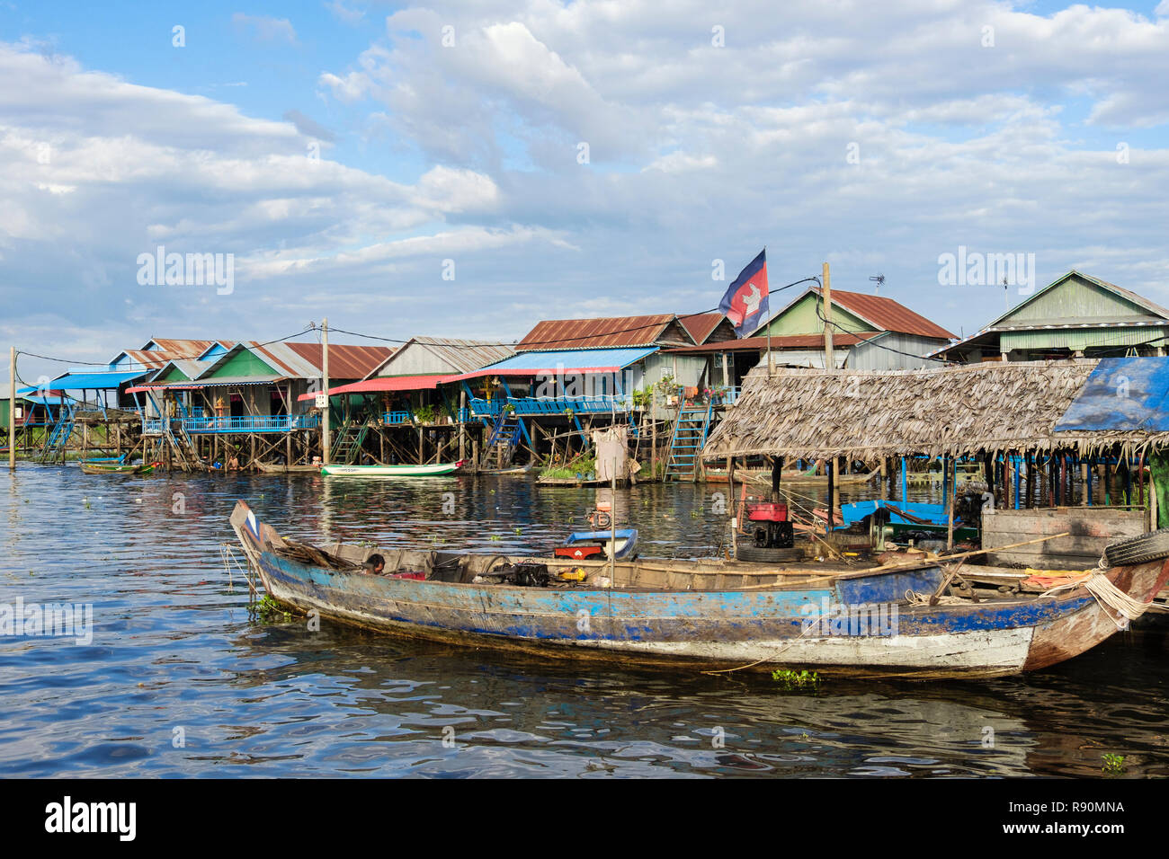 Vecchia barca in legno e case tradizionali su palafitte in floating villaggio di pescatori nel lago Tonle Sap. Kampong Phluk, Siem Reap provincia, Cambogia, Asia Foto Stock