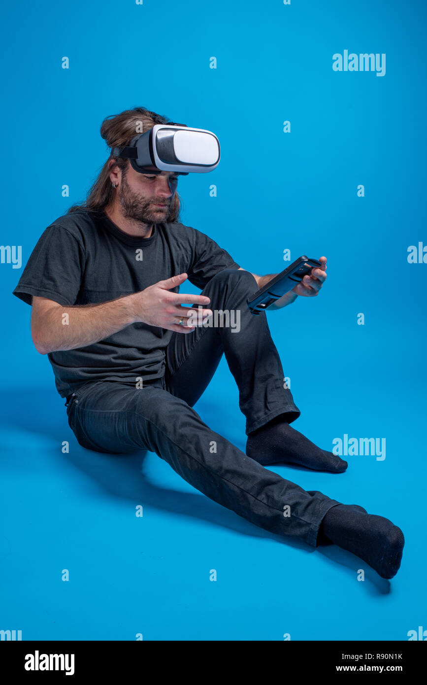 L'uomo ritratto cercando di configurare un dispositivo VR. Intrattenimento digitale e hi-tech innovazione Foto Stock