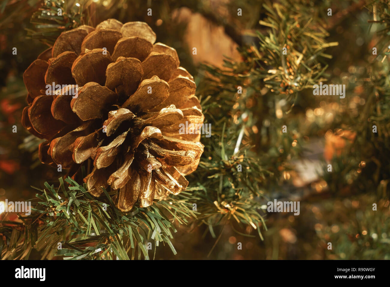 Macro di golden pigna in albero di Natale artificiale, con sfondo sfocato e copia di spazio. Foto Stock